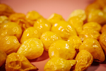 Glossy yellow dried chili fruits form a circular frame on a soft pink background, creating a vibrant and artistic composition with ample copy space in the center.