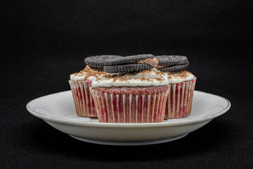 close up of various sweet cupcakes on cake stand isolated on black