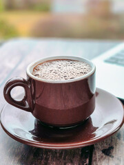 Cup of coffee on wooden table by window with laptop and books, business and training concept