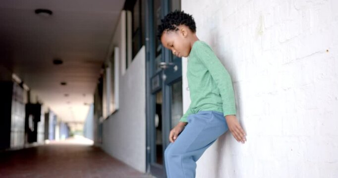 In school, upset boy sitting on the ground, feeling lonely or bullied