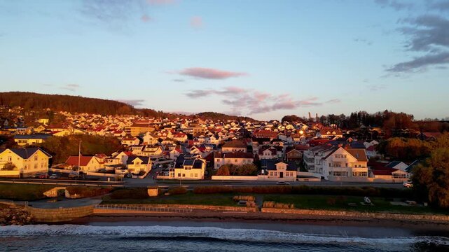 Beautiful sunset view of Larvik, Norway, with warm golden light illuminating the coastal town, colorful houses, and scenic shoreline.