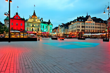 Fototapeta premium Colorful City Square at Dusk: Buildings Glow with Vibrant Hues Under a Twilight Sky