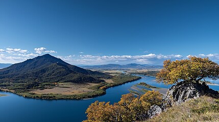 Obraz premium Scenic panoramic view of a river winding through vibrant autumn foliage and mountains