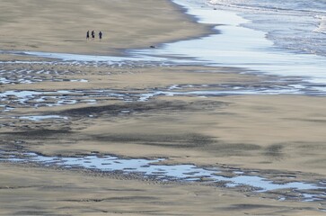 White Cliffs Beach at low tide, three men walking in the distance, rocks in the surf, Ahititi, Taranaki, North Island, New Zealand, Oceania