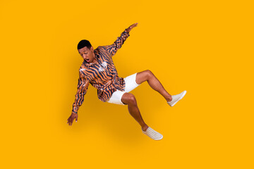 Young stylish man wearing animal print shirt, posing dynamically against vibrant yellow background