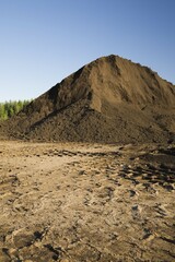 Heavy tire tracks and a mound of topsoil in a commercial sandpit, Quebec, Canada, North America