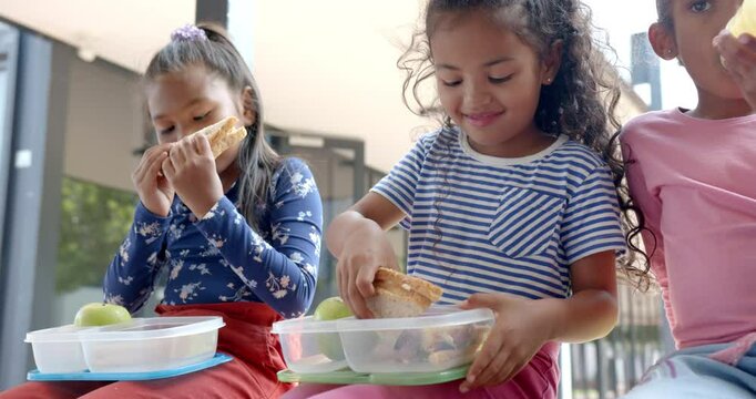 In school, three young biracial girls are enjoying lunch