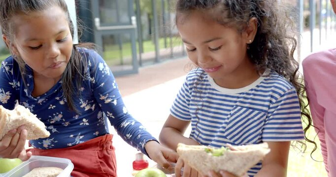 In school, children eating lunch together, enjoying sandwiches and apples