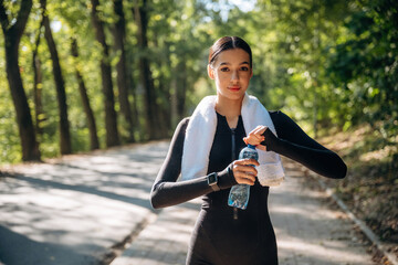 Young sportive skinny woman is in black fitness clothes outdoors