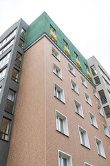 Contemporary building with brick facade, green rooftop, yellow accents, against bright sky. Urban architecture concept low angle view