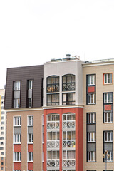 Contemporary apartment building with varied facade styles and balconies, featuring neutral and bold colours, under bright sky