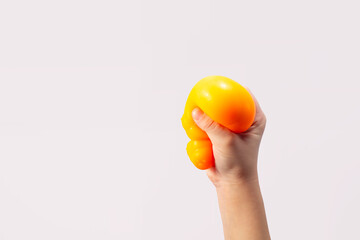 Hand squeeze orange stress ball on green background. Positive thinking concept