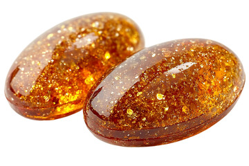 Two Shiny Oval Caramel Candies with Golden Specks on Black Backg