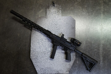 Steel target and tactical rifle with silencer in shooting range.
