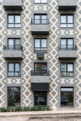 Fototapeta premium Modern building with a geometric brick pattern, featuring balconies with metal railings and windows, urban concept, front view