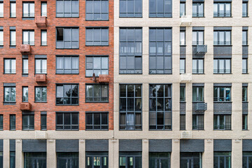 Contemporary multi-story buildings with beige, red brick and glass facades, showcasing balconies and windows. Urban architecture concept, front view