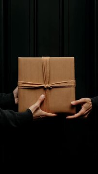 Hand holding a wrapped package at a black door. Ideal for Social Media, Stories