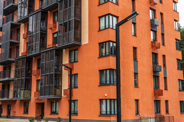Obraz premium Contemporary apartment building with orange facades, featuring numerous balconies with dark-framed windows. Urban housing concept