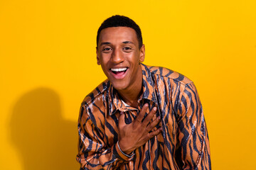 Young man smiling brightly in vibrant outfit against a yellow background, showcasing fashion and...