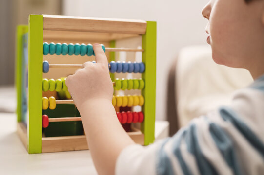 5 year old boy learning to count on colored wooden abacus. Child development and preschool education. kindergarten. Educational games for toddlers. World Autism Awareness Day