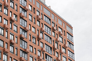Contemporary multi-story buildings with red brick and glass facades, showcasing balconies and windows. Urban architecture concept, low angle view
