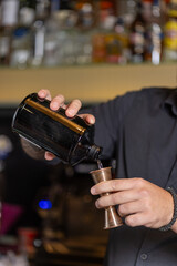 Bartender is measuring the drink for the cocktail.