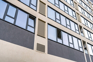 Modern building facade with large dark-framed windows and ventilation panels, showcasing clean architectural lines. Urban architecture concept