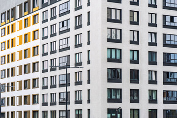 Modern multi-story apartment building with contrasting colours and large dark-framed windows. Urban residential concept