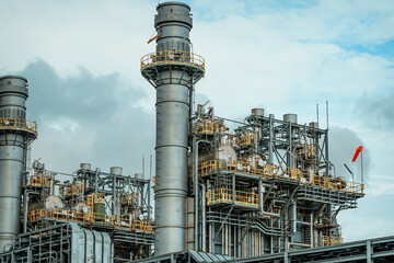 Industrial power plant with smokestacks and windsock under cloudy sky on a calm day