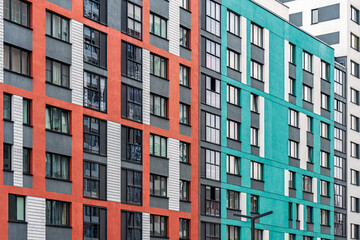 Red and teal modern building exteriors with geometric patterns, dark-framed windows, urban background, concept of contemporary architecture