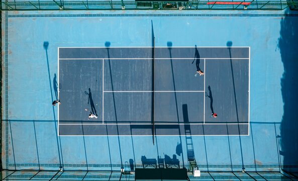 Aerial view of a doubles tennis match on a blue court.
