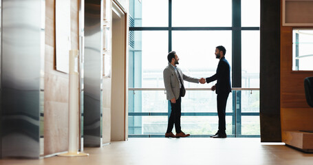 Business, men and shaking hands in office for meeting, b2b partnership and greeting for cooperation. Handshake, smile and team introduction, welcome and hello at conference hallway in hotel lobby © peopleimages.com