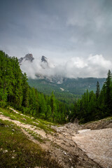 Mountain trail in the Dolomites (Dolomiti, Dolomiten), Italy, leading to Lago Sorapis. The path winds along rocky slopes with stunning views of valleys, forests, and peaks