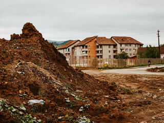 Pile Of Dirt And Debris In A Construction Site Near Residential Buildings: A Muddy Urban Landscape...