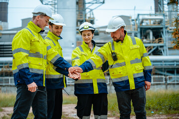 Team of workers in safety gear collaborating at industrial site during daytime