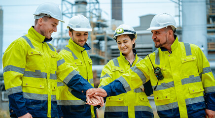 Team of industrial workers collaborating at a construction site wearing safety gear and helmets in...