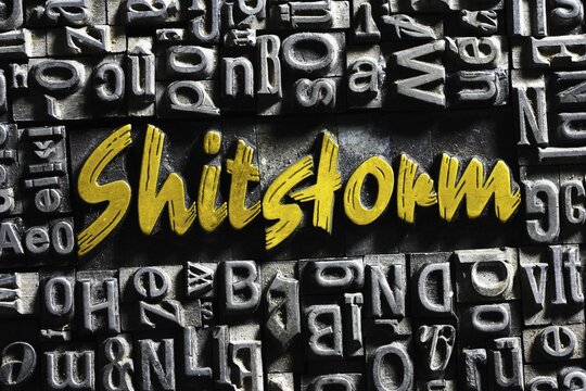 Old lead letters with golden writing, word shitstorm