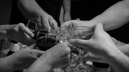Group of friends clinking glasses with red wine in black and white
