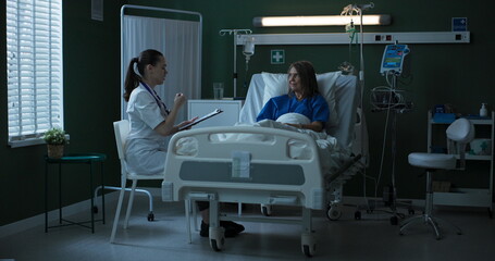 Doctor seated beside elderly patient, providing document for her to sign.