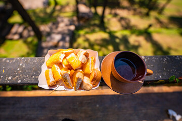 Hot coffee on a clear morning with pine trees lining the green forest under a blue sky. Green grass...