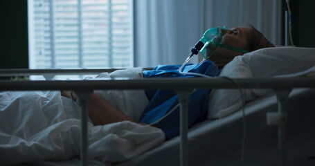 Elderly patient lies in bed with an oxygen mask, struggling with respiratory illness.