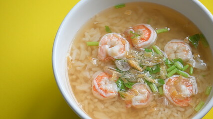 rice soup with shrimp in white bowl on yellow background
