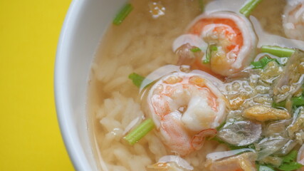 rice soup with shrimp in white bowl on yellow background