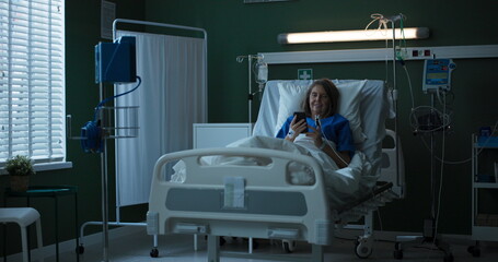 Elderly woman in hospital room, chatting on phone via video call, bringing smiles.