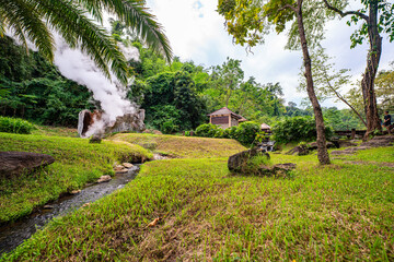 Fang hot spring. A scenic view of a natural hot spring emitting steam in a lush tropical forest....