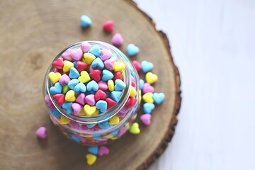 A photo of a jar filled with colorful mini hearts