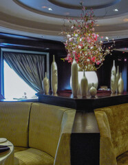 Art Deco interior design style furniture, carpets and paneling onboard modern ocean liner cruiseship cruise ship main dining room restaurant with flower deco and set tables