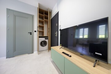 Salon w nowoczesnym apartamencie z seledynowym aneksem kuchennym z ciemnozieloną sofą © arteffect.pl