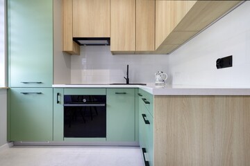 Kuchnia w nowoczesnym apartamencie w kolorze seledynowym i jasno brązowym