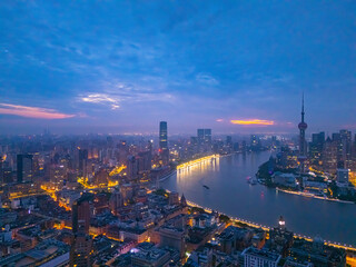 Naklejka premium Aerial view of Shanghai skyline and bright city streets at dawn